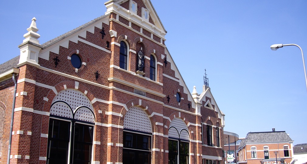 Historisch bakstenen gebouw met ronde ramen en witte accenten onder een heldere blauwe lucht in Nederland.