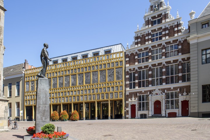 Beeld van een plein met standbeeld en karakteristieke gebouwen, waaronder een modern raadhuis in Nederland.