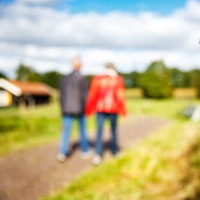 Oranje wandelroutepaal met opschrift N31 en wandelnetwerk Twente, twee wandelaars op de achtergrond