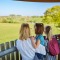 Gezin van vier geniet van het uitzicht over een groen landschap vanaf een houten uitkijktoren.