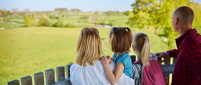 Gezin van vier geniet van het uitzicht over een groen landschap vanaf een houten uitkijktoren.