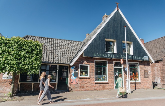 Zwei Frauen gehen am Bäckerei- und Fischmuseum in einem typisch niederländischen Dorf vorbei.