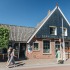 Twee vrouwen lopen langs het Bakkerij & Vis Museum in een karakteristiek Nederlands dorp.