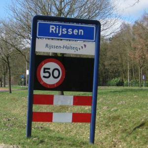 Verkeersbord bij de ingang van Rijssen met snelheidslimiet van 50 km/u en bomen langs de weg.