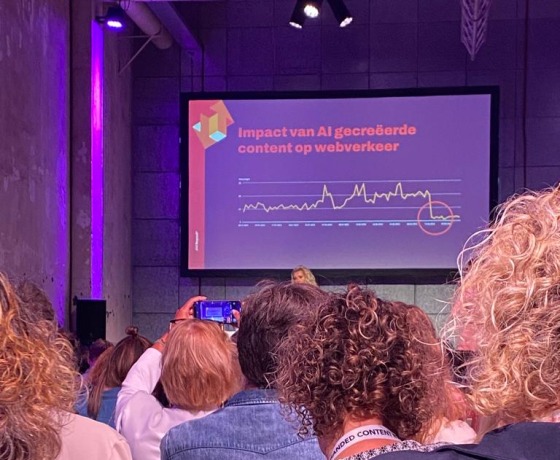 Een conferentiepresentatie toont een grafiek over de impact van AI-gecreëerde content op webverkeer.