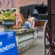 Twee jonge kinderen bewonderen historische koetsen tijdens Open Monumentendag, met bloemen op de voorgrond.