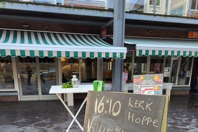 Bord met schema en welkomsgroet voor een evenement, met kerstboomtekening en de tekst 'merry crisism'.