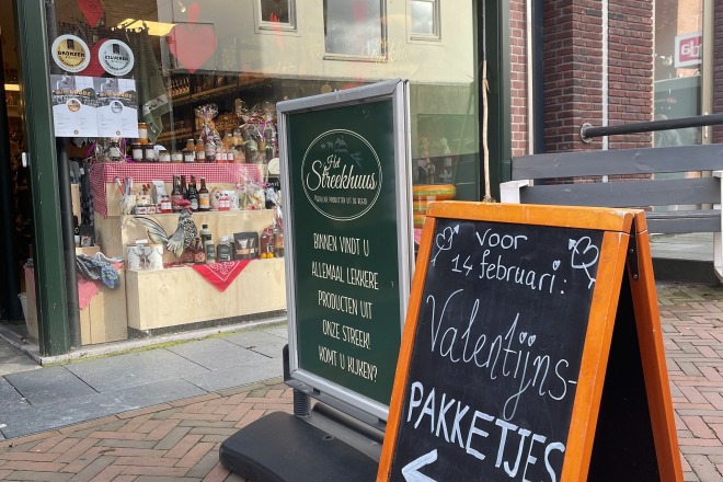 Buitenaanzicht van een winkel met een bord waarop geadverteerd wordt voor Valentijnspakketjes.