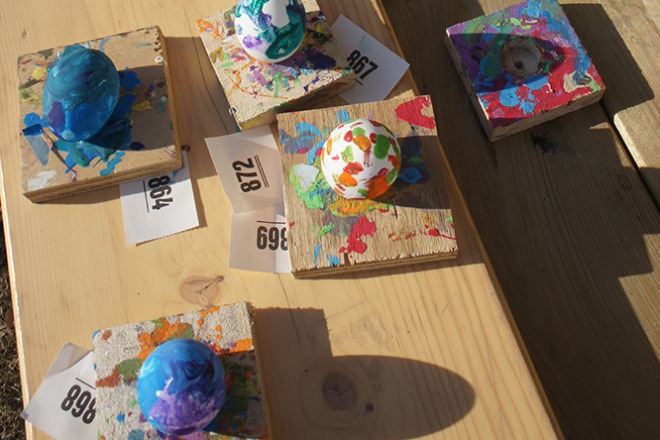 Geverfde paaseieren op houten blokjes, tentoongesteld op een tafel, met genummerde kaartjes.