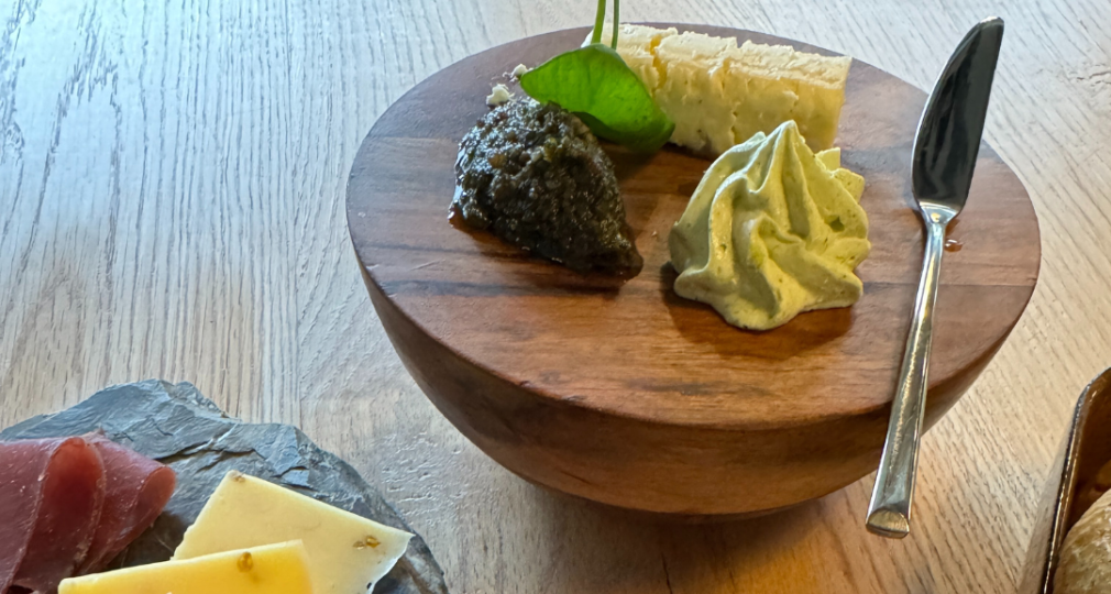 Een gourmetselectie met kaas, vleeswaren, gefrituurde balletjes en dips op een houten tafel.