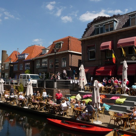 Terras aan het water in een Nederlands stadje met mensen die genieten van het zonnige weer.