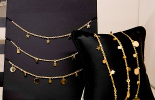 Etalage met gouden armbanden en kettingen met ster- en muntvormige hangers, prijskaartje €19,99.