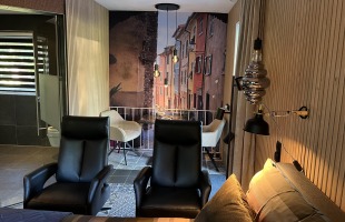 Een moderne woonkamer met zwarte stoelen en een trompe-l'oeil muurschildering van een straatje.