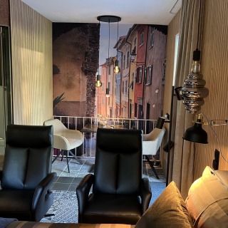 Een moderne woonkamer met zwarte stoelen en een trompe-l'oeil muurschildering van een straatje.