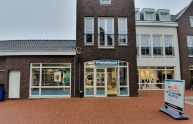 Buitenzicht op PhoneHouse winkel met grote ramen, reclamebord en Terstal kledingwinkel op de achtergrond.