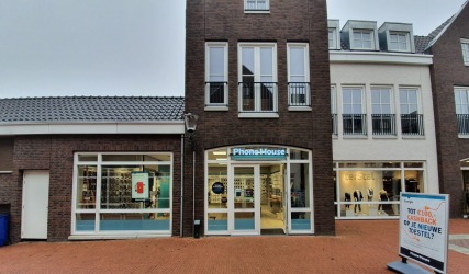 Buitenzicht op PhoneHouse winkel met grote ramen, reclamebord en Terstal kledingwinkel op de achtergrond.