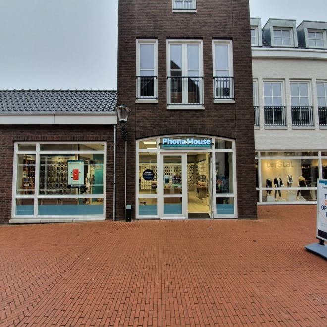 Buitenzicht op PhoneHouse winkel met grote ramen, reclamebord en Terstal kledingwinkel op de achtergrond.