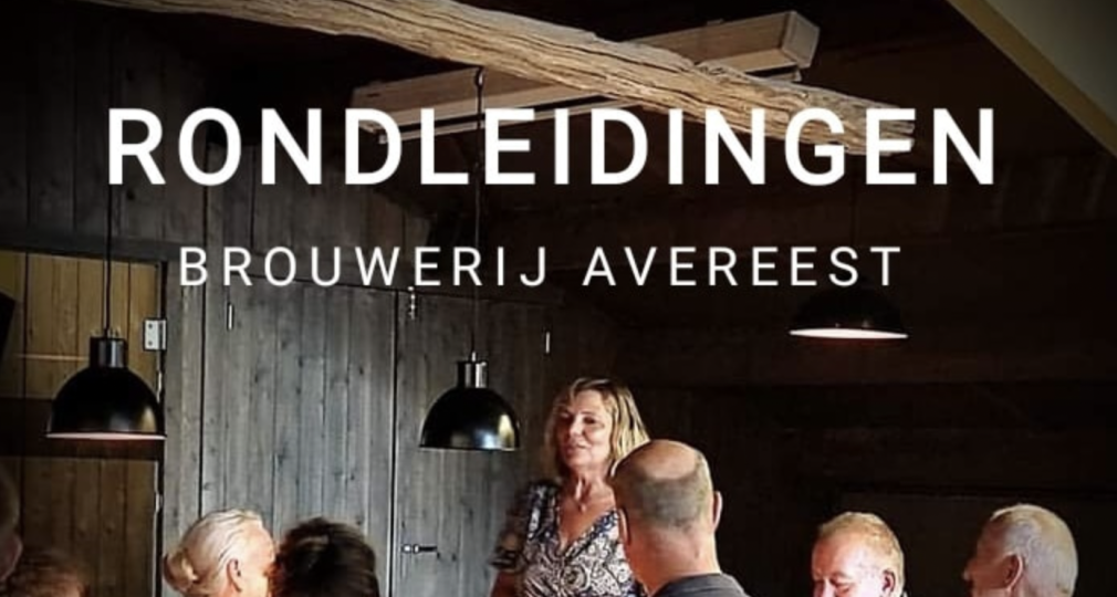 Groep mensen krijgt een rondleiding bij Brouwerij Avereest, vrouw spreekt aan tafel met gasten.
