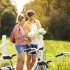 Twee mensen met fietsen bestuderen een kaart in een groen natuurgebied op een zonnige dag.