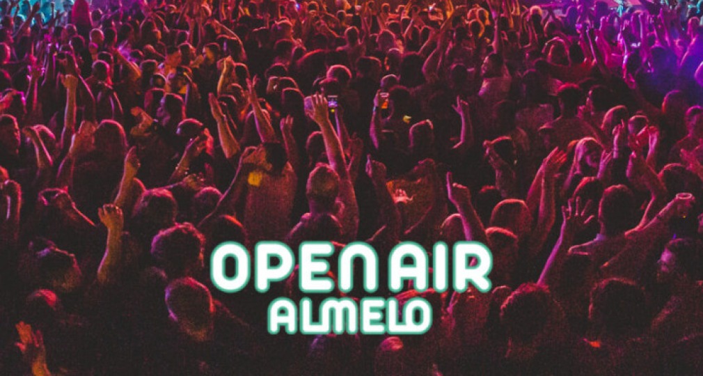 Een kleurrijk dansfeest bij Open Air Almelo met veel publiek en felle lichten rond een hoofdpodium.