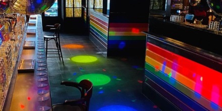 Lege nachtclub met regenboogstrepen, discoballen en kleurrijke lichten reflecteren op de vloer.