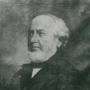 Zwart-wit portret van een oudere man met wit haar en baard, gekleed in formele kleding, tegen een donkere achtergrond.