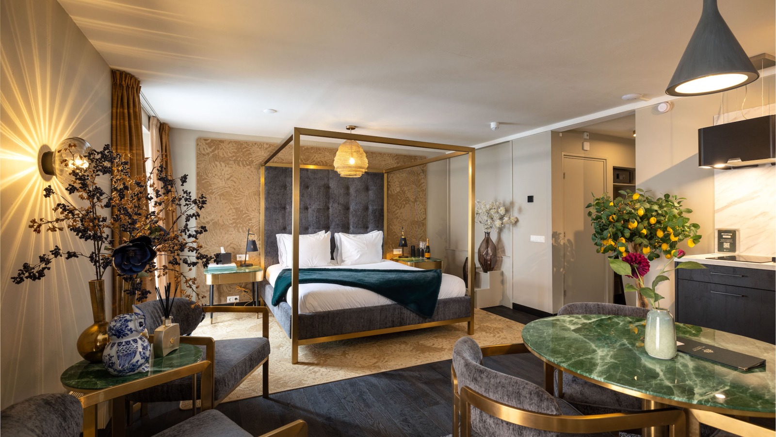 Luxe hotelsuite met hemelbed, groene marmeren tafel, elegante stoelen en sfeervolle decoratie.