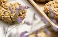 Vegan havermout-rozijnenkoekjes op een houten schaal met een prijsbordje van €3 in een zonnige bakkerij.