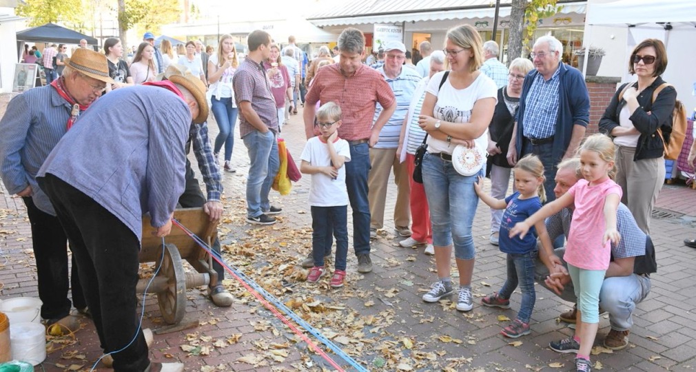 Menschen versammeln sich im Freien, um eine handwerkliche Vorführung auf einem Straßenfest zu sehen.