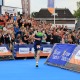 Triatleet rent naar de finish tijdens een wedstrijd met juichend publiek op de achtergrond in Nederland.