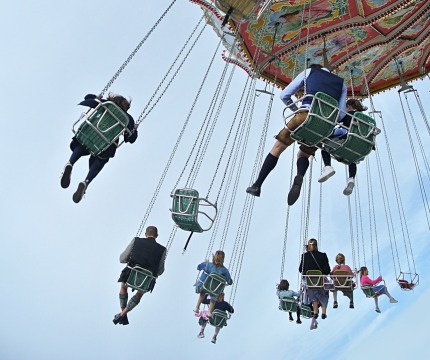 Mensen in kleurrijke stoelen genieten van een draaimolen zweefmolen tegen een heldere lucht op een kermis.