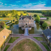 Luchtfoto van een historisch kasteel met slotgracht, symmetrische tuinen en omliggende natuur in Nederland.