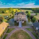 Luchtfoto van een historisch kasteel met slotgracht, symmetrische tuinen en omliggende natuur in Nederland.