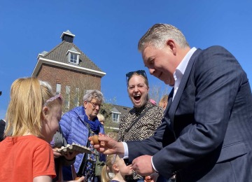 Mensen spelen een eitikkenspel buiten op een zonnige dag; een man en een meisje tikken eieren tegen elkaar.