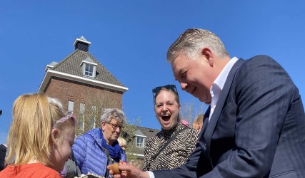 Mensen spelen een eitikkenspel buiten op een zonnige dag; een man en een meisje tikken eieren tegen elkaar.