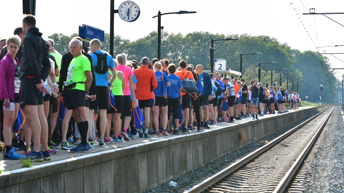 Een grote groep hardlopers verzamelt zich op het perron bij station Dalfsen, klaar voor een evenement.