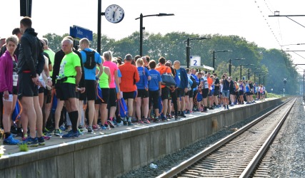 Een grote groep hardlopers verzamelt zich op het perron bij station Dalfsen, klaar voor een evenement.