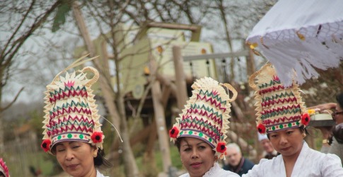 Traditionele Indonesische danseressen in kleurrijke kleding en hoofdtooien voeren een groepsdans uit buiten.
