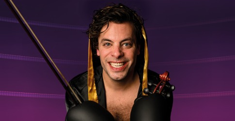 Man in een zwarte en gouden bokscape met bokshandschoenen, viool en strijkstok voor een paarse achtergrond.