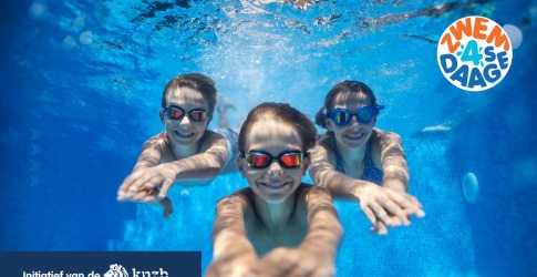 Drie kinderen zwemmen onder water met zwembrillen tijdens de Zwem4Daagse, initiatief van de KNZB.