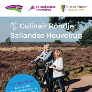 Twee vrouwen fietsen op de Sallandse Heuvelrug tussen paarse heide, flyer voor culinair rondje.