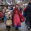 Groep mensen in Dickens-kostuums loopt door een sfeervolle straat tijdens het Dickens Festijn.