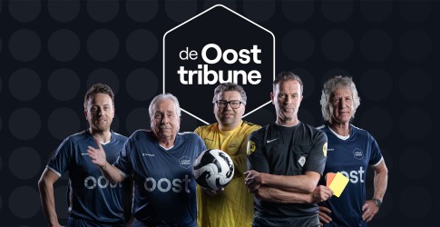 Vijf mannen in voetbaloutfits en scheidsrechter bij de Oost Tribune, met een voetbal en gele kaart.