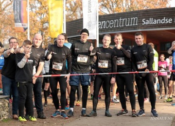 Groep hardlopers poseert lachend bij startlijn tijdens sportevenement bij het bezoekerscentrum.