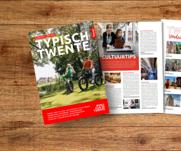 Een tijdschrift getiteld 'Typisch Twente' ligt open op een houten tafel, met pagina's over cultuur.