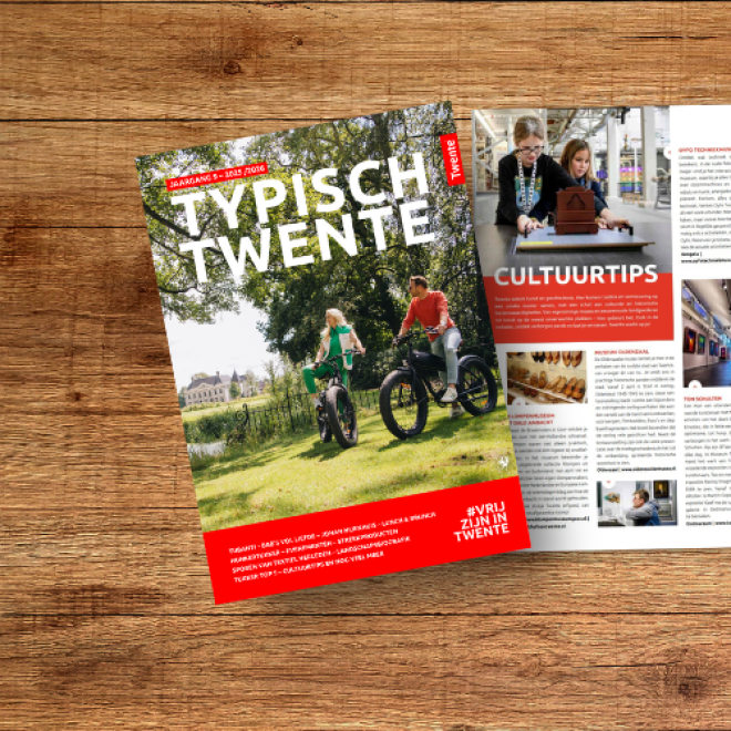 Een tijdschrift getiteld 'Typisch Twente' ligt open op een houten tafel, met pagina's over cultuur.