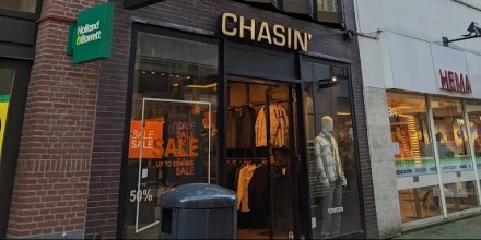 Smalle winkel met opvallende moderne gevel en grote ramen, gelegen tussen bredere traditionele panden.