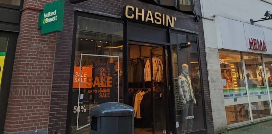 Smalle winkel met opvallende moderne gevel en grote ramen, gelegen tussen bredere traditionele panden.