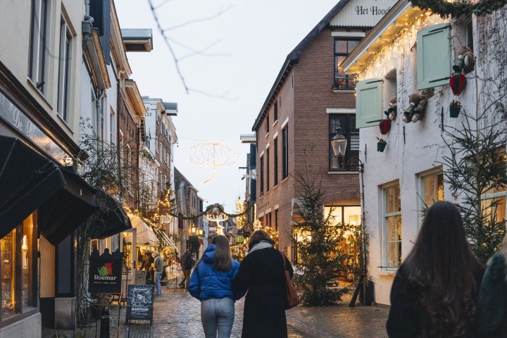 Sfeervol verlichte winkelstraat in Nederland tijdens de feestdagen met mensen die wandelen in de avond.