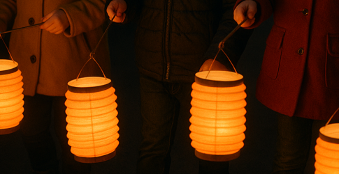 Drie lachende kinderen in warme jassen houden oranje lantaarns vast tijdens een nachtelijke optocht.